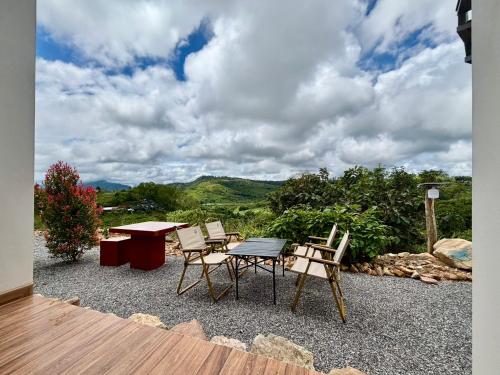 a patio with a table and chairs with a view of mountains at เขาลมเย็น in Khao Kho