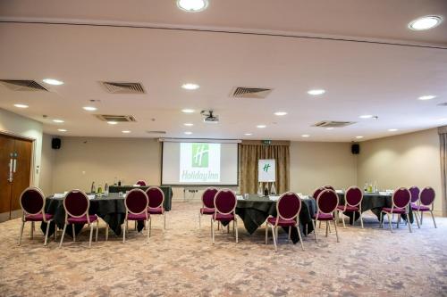 a conference room with tables and chairs and a screen at Holiday Inn Newcastle South by IHG in Boldon