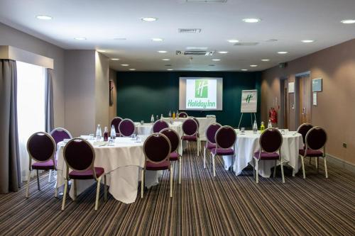 a conference room with tables and chairs and a screen at Holiday Inn Newcastle South by IHG in Boldon