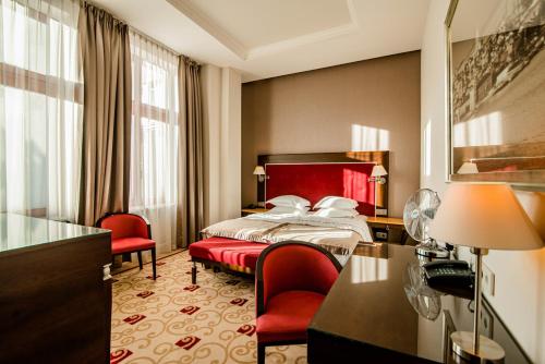 a hotel room with a bed and two red chairs at Hotel Dyplomat in Olsztyn