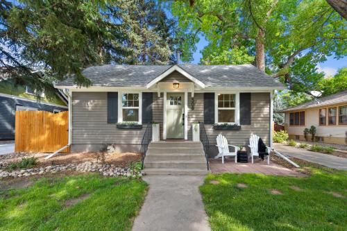 una casa gris con dos sillas blancas en un porche en Shade Tree Bungalow in Old Town, Yard & Garage, en Buckingham