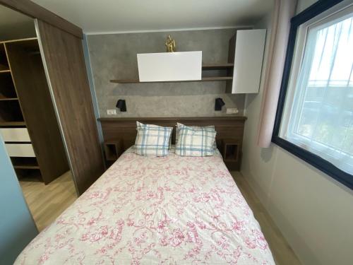 ein kleines Schlafzimmer mit einem Bett mit einer rosa Decke in der Unterkunft Douce Escale in Lège-Cap-Ferret