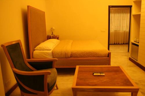a bedroom with a bed and a chair and a table at The Enterprise in Karachi