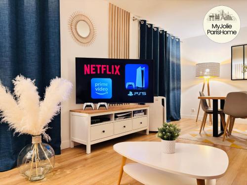 a living room with a tv and a table at MyJolieParisHome - King size bed, Balcony, 2 Parking in Paris