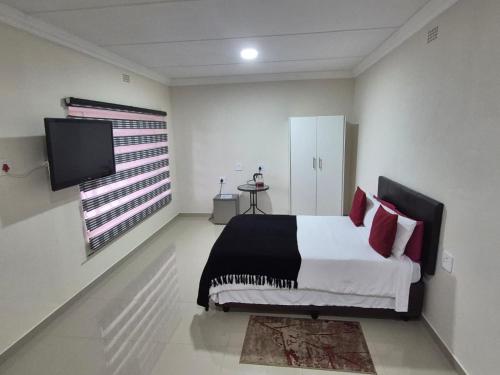 a bedroom with a bed and a flat screen tv at Ithonsi Guesthouse in Kempton Park