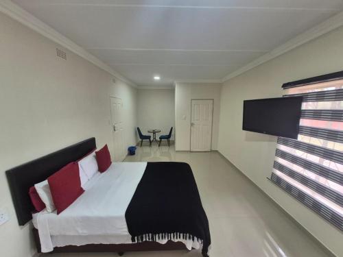 a bedroom with a bed and a flat screen tv at Ithonsi Guesthouse in Kempton Park