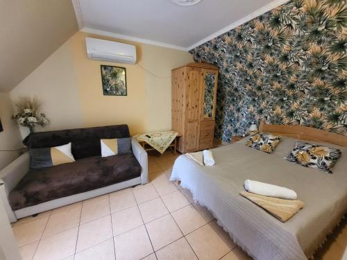 a bedroom with a bed and a couch at Liget Nyaralóház és Apartman Liget in Szilvásvárad