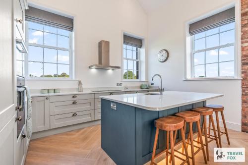 a kitchen with a blue island with bar stools at The Old Chapel in Dilhorne