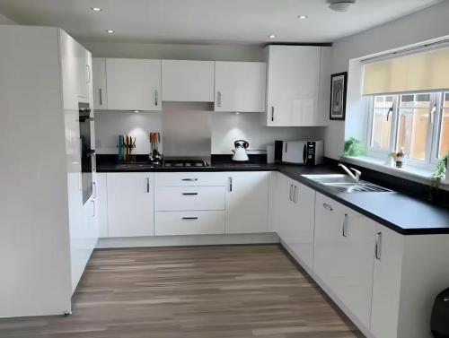 a white kitchen with white cabinets and a sink at Spacious & Stylish 4-Bed House with Hot Tub in Prime Location in Southampton