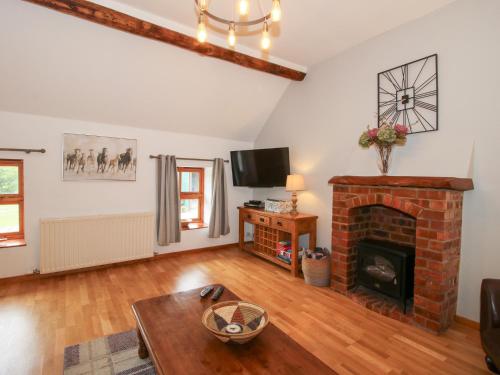 a living room with a fireplace and a tv at Old Hall Barn 3 in Church Stretton