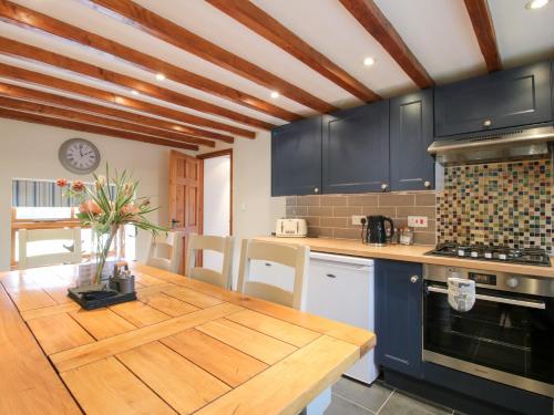 a kitchen with blue cabinets and a wooden table at Old Hall Barn 3 in Church Stretton