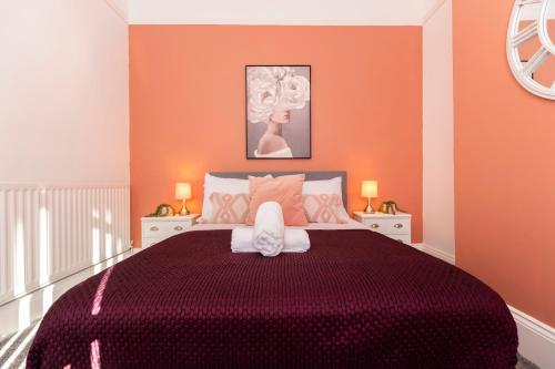 a bedroom with a large purple bed with orange walls at Newly Renovated 3br House Near Hospital & Uni in Sunderland