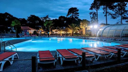 una piscina con lettini e un edificio di Douce Escale a Lège-Cap-Ferret