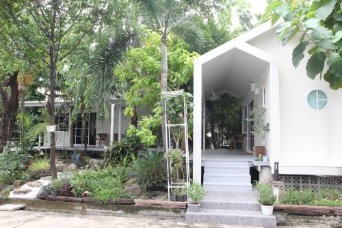 a white house with trees in front of it at Homeku Guesthouse Room 3 Cozy Stay Close to Suvarnabhumi Airport in Lat Krabang