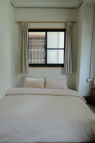 a bedroom with a white bed and a window at Tomo 伴 in Tainan