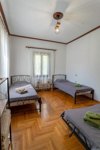 a room with two beds and a wooden floor at Tasos Apartment in Leonidio