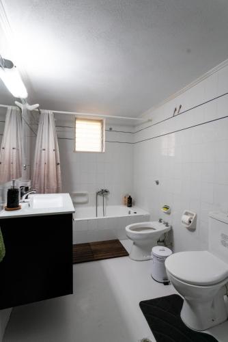 a bathroom with two toilets and a sink and a tub at Tasos Apartment in Leonidio