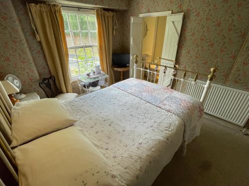 a bedroom with a bed and a mirror and a window at The Bridge Street Historic Guest House in Sudbury