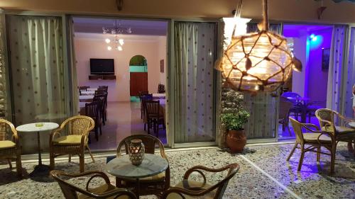 a dining room with tables and chairs and a chandelier at Hermes in Agia Marina Aegina