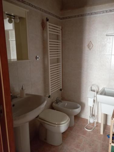 a bathroom with a white toilet and a sink at Casa Checco in Cisternino