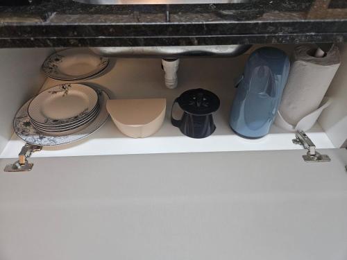 a drawer under a sink with plates and pans at Travellar Apt 91 - Admirável - Monte Carmelo in Ribeirão Preto