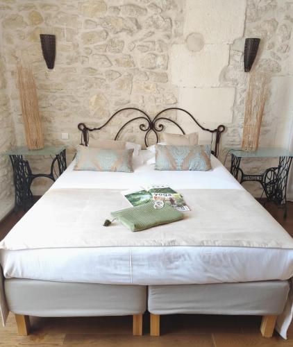 a bedroom with a large white bed with two tables at Hôtel Mas Vidau Porte des Alpilles in Saint-Étienne-du-Grès