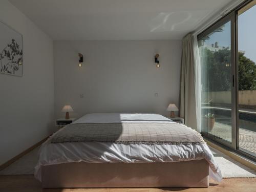 a bedroom with a bed and a large window at Dom Carlos Villa in Vila Nova de Gaia