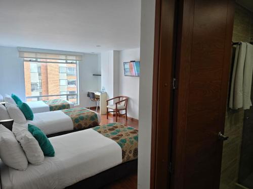 a hotel room with two beds and a window at Hotel Castellana 100 Bogota By Hoteles Confort 80 in Bogotá
