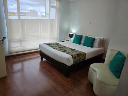 a bedroom with a large bed and a chair at Hotel Castellana 100 Bogota By Hoteles Confort 80 in Bogotá