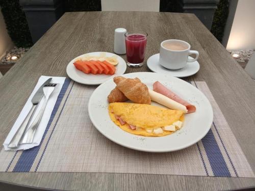 a table with two plates of breakfast foods and a cup of coffee at Hotel Castellana 100 Bogota By Hoteles Confort 80 in Bogotá