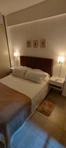 a bedroom with a large bed with two tables and two lamps at Departamento Temporario Tucuman 3Personas Pileta in San Miguel de Tucumán