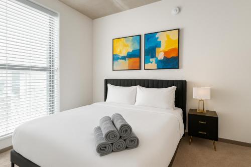 a bedroom with a white bed with towels on it at Stylish 2BR Rooftop Views plus Sky Lounge in Birmingham