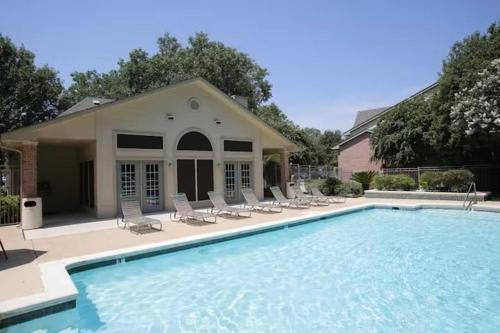 a swimming pool with chairs and a house at Cozy 1BR Apt near Baylor UMHB in Temple