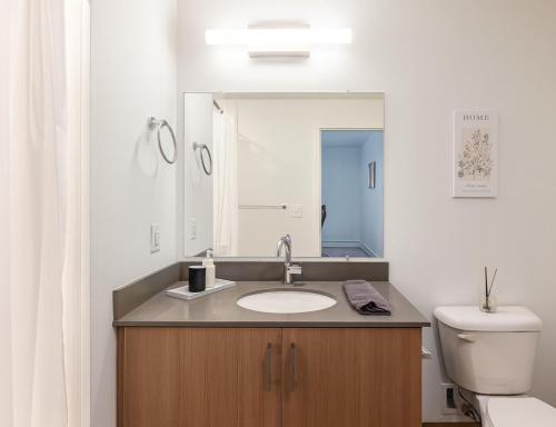 a bathroom with a sink and a toilet and a mirror at Bright 2BR Apt Pool, Gym Walkable Area in Birmingham