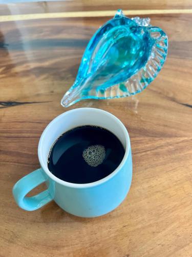 a cup of coffee and a shell on a table at Casa Tortuga Cabo Paradise in Cabo San Lucas