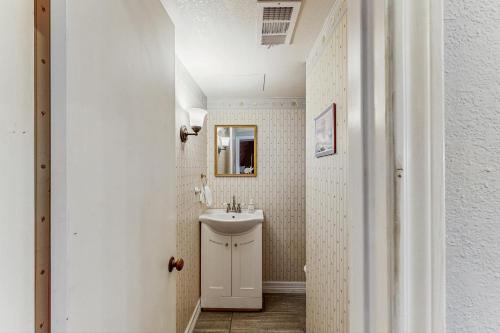 a white bathroom with a sink and a mirror at Tiki Hideaway in Village of Tiki Island