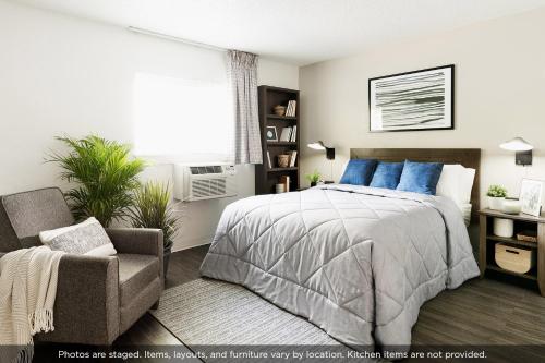a bedroom with a bed and a chair and a window at InTown Suites Extended Stay Matthews NC - East Independence in Charlotte