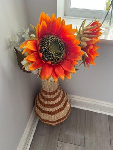 a vase with a large orange flower in a room at Beach Front House in Walton-on-the-Naze
