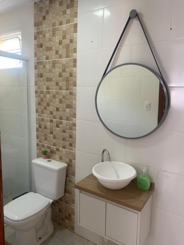 a bathroom with a toilet and a sink and a mirror at Casa de férias no Estreito! in Florianópolis