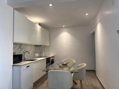 a kitchen with a glass table and white cabinets at Loft Story in Lisbon Humberto Delgado Airport