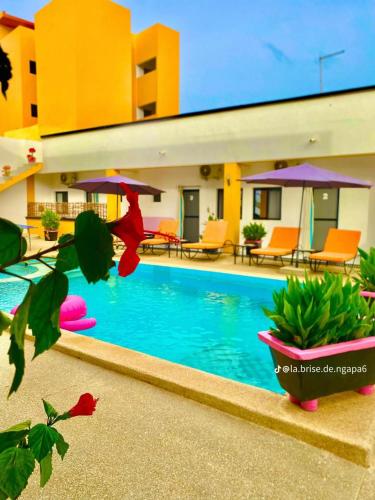 a pool in front of a building with chairs and umbrellas at La Brise de Ngaparou in Ngaparou