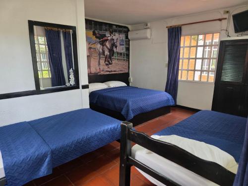 a bedroom with two beds and a painting on the wall at Hotel Campestre Kosta Azul in Villavicencio