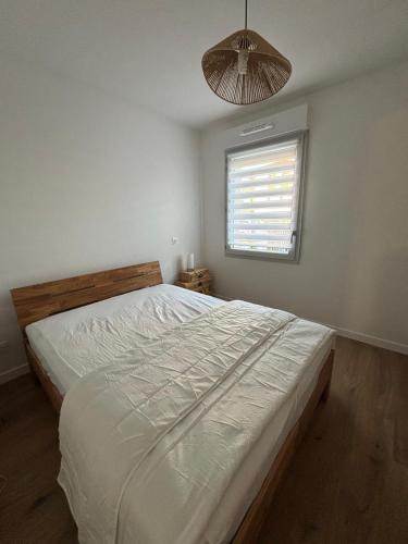 a bedroom with a large white bed with a window at Appartement neuf in Linxe