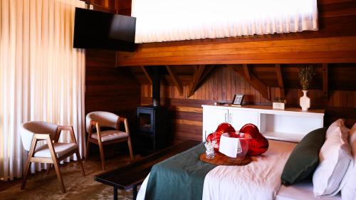 a bedroom with a bed and two chairs at Hospedaria Morada das Grimpas in Palmeira