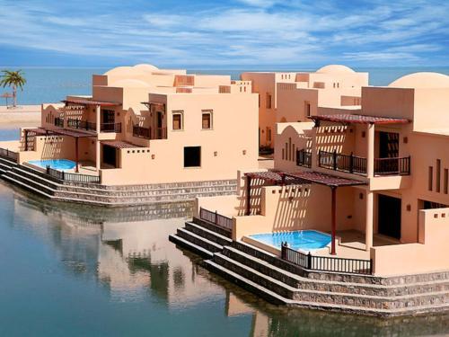 a group of houses sitting in the water at Exclusive 2BR Poolside Villa 5 Star Resort Escape in Ras al Khaimah