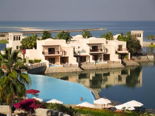 a resort with a swimming pool next to the ocean at Exclusive 2BR Poolside Villa 5 Star Resort Escape in Ras al Khaimah