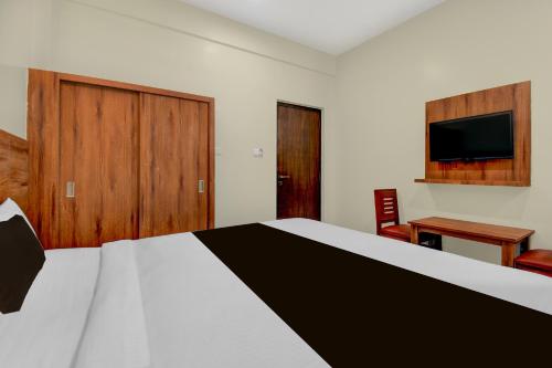 Un dormitorio con una cama, un escritorio y un televisor. en Hotel O Royal Stay, en Hirisāve