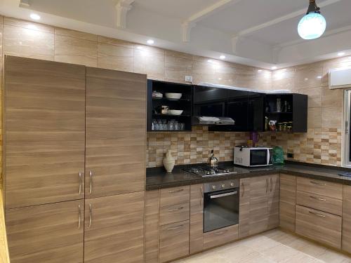 a kitchen with wooden cabinets and a microwave at haya abdun in Amman