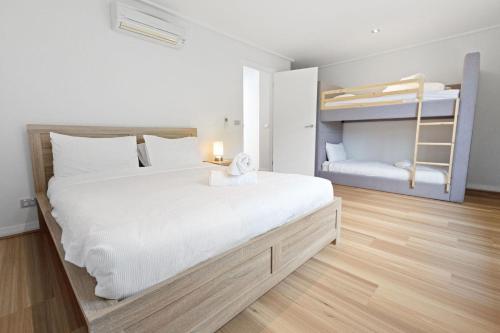 Un dormitorio con una cama grande y literas. en Blue Waters, en Lakes Entrance