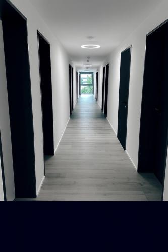 a hallway of an empty room with black doors at Munique Hotel München in Unterschleißheim